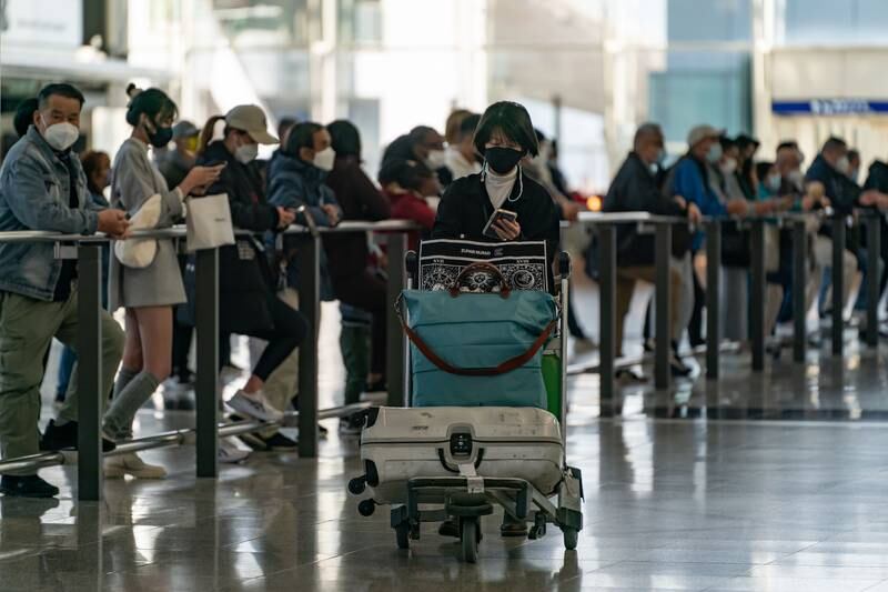 Travellers walk with their luggage at the arrivals hall of Hong Kong International Airport. Getty
