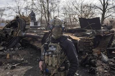 A Ukrainian serviceman walks past the wreck of a Russian tank in Lukyanivka, Kyiv. Reuters