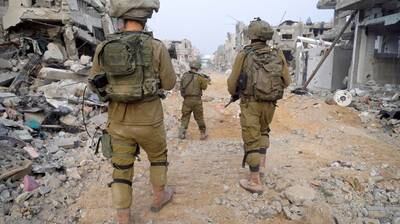Israeli soldiers walk past debris and damaged buildings at a location given as Gaza by Israel's military. Reuters