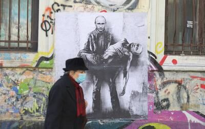 A woman walks past a poster depicting Russian President Vladimir Putin holding his own body, as Russia's invasion of Ukraine continues, in Sofia, Bulgaria. Reuters