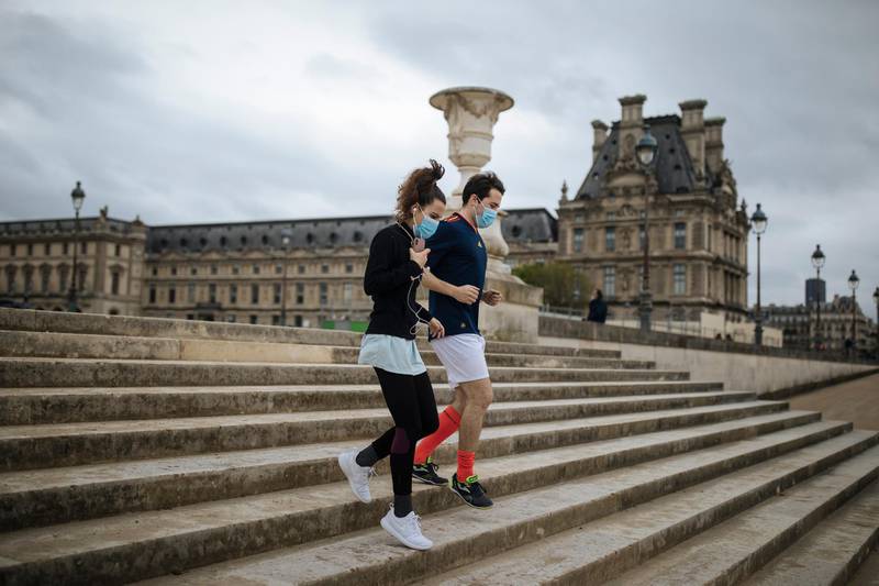 A masked couple run down the steps of the Tuileries Garden, in Paris, France. AP Photo