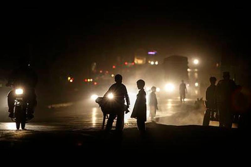 Pakistanis are silhouetted against vehicle headlamps while walking on street darkened by power cuts, on the outskirts of Islamabad, Pakistan, Tuesday, June 4, 2013. Much of Pakistan is subject to rolling power cuts up to 18 hours a day because of electricity shortages. (AP Photo/Muhammed Muheisen)