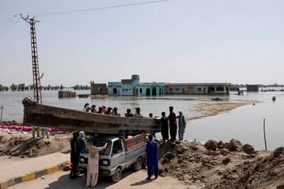People launch a wooden boat into rising floodwaters in Mehar, Pakistan. Reuters