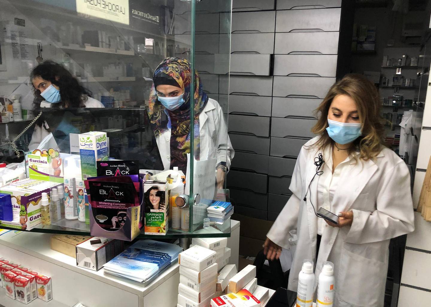 Pharmacist Siham Itani wearing a protective mask looks at her mobile phone inside her pharmacy in Beirut, Lebanon October 6, 2020. Picture taken October 6, 2020. REUTERS/Issam Abdallah