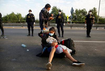 A woman holding a child sits on a motorway surrounded by police while Peruvians who were stranded in Lima during an ongoing quarantine try to make their way to San Martin and other parts of the country, in Lima, Peru. Reuters
