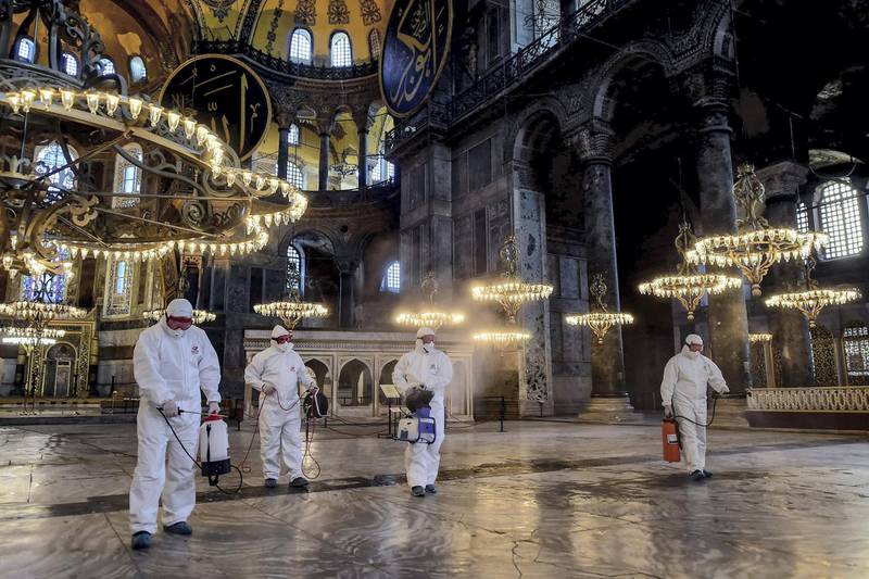 TOPSHOT - Employees of the Fatih Municipality wearing protective suits disinfect the Hagia Sophia to prevent the spread of the COVID-19, caused by the novel coronavirus, in Istanbul, on March 13, 2020. Turkey announced on March 11, 2020 its first coronavirus case, a man who had recently travelled to Europe and is in good health. Turkey has announced several measures in recent weeks to try and stop the virus reaching the country, including thermal cameras at airports, cancelling flights to affected countries and closing its border with Iran. / AFP / Yasin AKGUL

