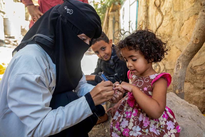 A Yemeni health worker marks a child with a marker after administering the polio vaccine as part of an immunisation campaign in Yemen's third city of Taez, on February 19, 2022.  (Photo by AHMAD AL-BASHA  /  AFP)