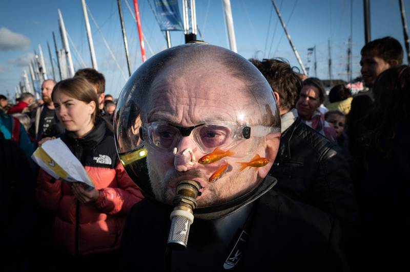 A man wearing an aquarium with goldfishes on his head walks among the pedestrians at the 'Village de Saint-Malo', the start point of the Route du Rhum solo sailing race, in Saint-Malo. The Route du Rhum solo sailing race starts on November 6, 2022, from Saint-Malo to  Pointe-a-Pitre in Guadeloupe. AFP