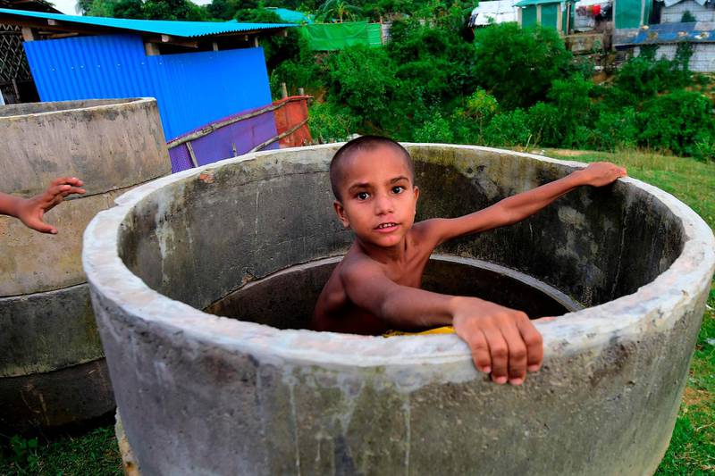 A Rohingya child sits inside a sewage ring at a camp in Teknaf. AFP
