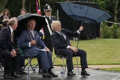 The prime minister battles with his umbrella while with Prince Charles at The National Memorial Arboretum in July 2021, in Stafford, England. Getty Images