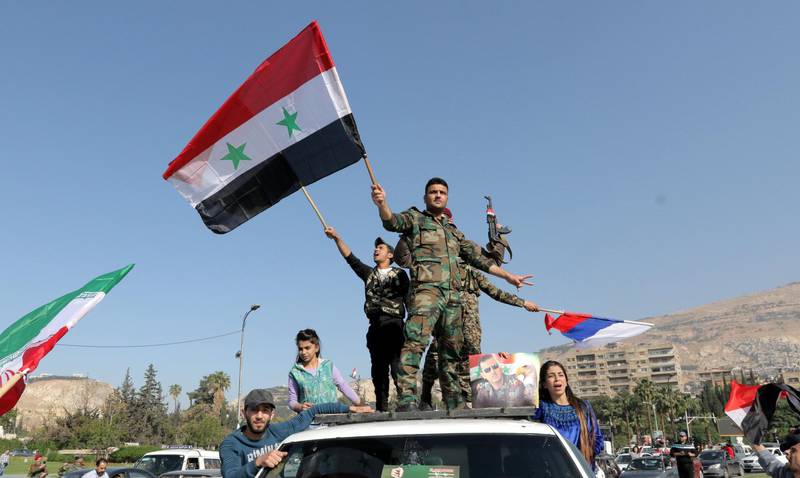 Soldiers waved the national flag as well as Iranian and Russian ones. Youssef Badawi / EPA
