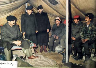 A reproduction of a picture displayed at the Nasr or Victory Museum in Baghdad shows Iraqi President Saddam Hussein (L) visiting Iraqi troops at a military camp in occupied territory in Kuwait after the August 2, 1990 invasion of the Gulf emirate. The Nasr Museum is dedicated to the Iraqi leader and includes painting made of and for him, uniforms and weapons he used during the 1991 Gulf War and official gifts he received during his two-decade reign. The 10th anniversary of the Gulf War, when a US-led international coalition unleashed a war to liberate Kuwait from Iraqi occupation, is coming up 16 January 2001. AFP PHOTO/Karim SAHIB
AFP PHOTO AFP/KARIM SAHIB/mro (Photo by AFP)