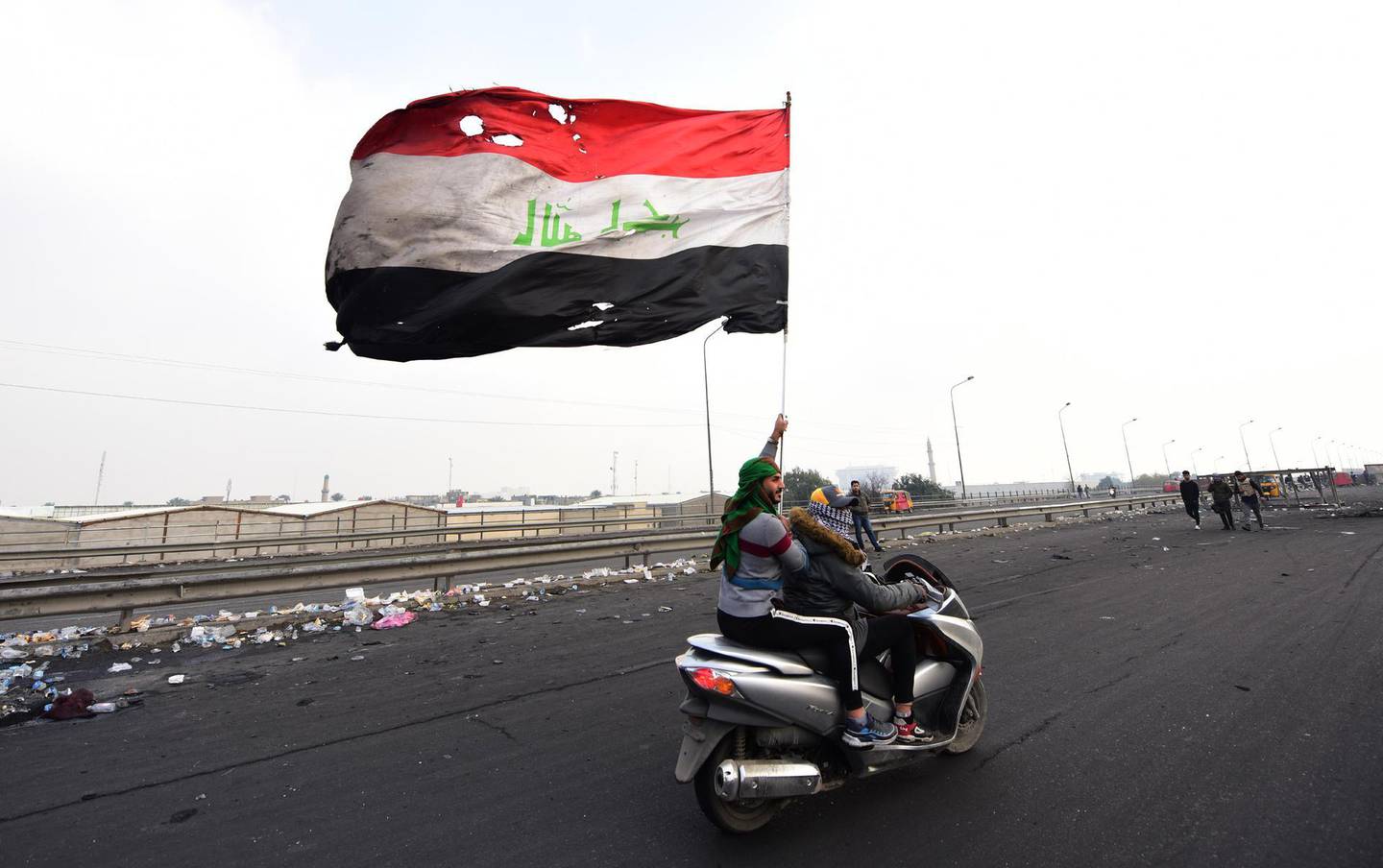 epa08155171 An Iraqi protester waves the Iraqi national flag during a protest in central Baghdad, Iraq, 23 January 2020. The death toll from clashes between protesters and Iraqi security forces rose to 12 victims from the protesters, as protesters continued closing the main roads in central Baghdad and gathering in Tahrir Square to protest against the Iraqi government.  EPA/MURTAJA LATEEF