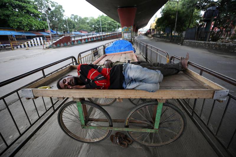 Homeless men sleep on a handcart parked on a road divider in a containment zone during lockdown in Bengaluru, India. AP Photo