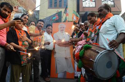 Indian supporters and BJP workers celebrate with sparkles during the swearing-in ceremony. AFP