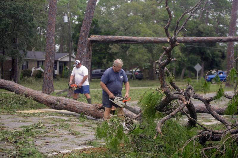 Tyler Haas, left, and his father Ed Haas saw a tree to clear the road after Hurricane Sally made landfall, in Dauphin Island, Alabama, U.S. REUTERS