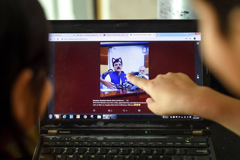 Pakistani children point at a computer screen showing a screen grab of a press conference attended by provincial minister Shaukat Yousafzai and streamed live on social media, in Islamabad on June 15, 2019.  A minister in Pakistan's northwestern Khyber Pakhtunkhwa province had to face hilarious situation after his entire media talks went live with a cat filter on by his social media team. / AFP / FAROOQ NAEEM
