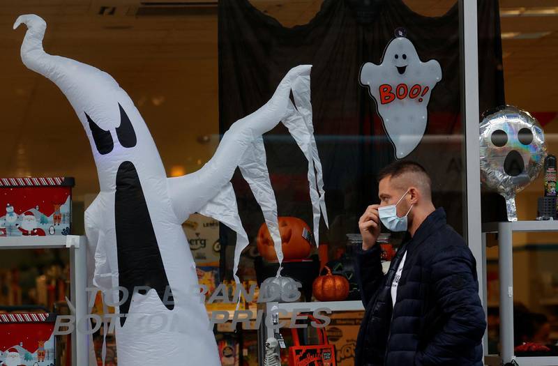 A man wears a face mask as he walks past a Halloween display in Liverpool. Reuters