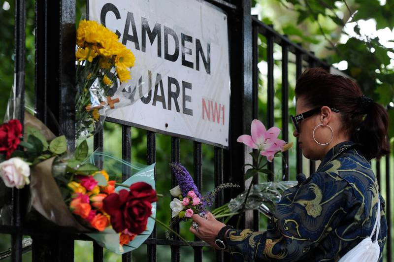 A woman ties flowers to a railing on July 24, 2011 near the house in north London where the body of pop star Amy Winehouse was found the previous day. The troubled British singer, whose struggle with drink and drugs overshadowed her sultry musical talents, has been found dead at her flat in north London, emergency services said. She was 27. AFP PHOTO/CARL COURT
 *** Local Caption ***  482675-01-08.jpg