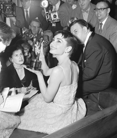 Audrey Hepburn, surrounded by photographers and reporters, holds up the Best Actress Oscar she won for her first US film Roman Holiday, at the 1954 Academy Awards. Getty Images