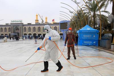 Iraqi health workers disinfect the area around the Imam Hussein Shrine (background) in the central Iraqi holy shrine city of Karbala on March 15, 2020 amidst efforts against the spread of COVID-19 coronavirus disease.  / AFP / Mohammed SAWAF
