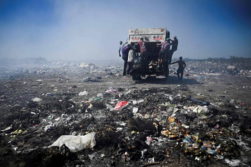 Recyclers cling to a waste lorry in Lujan, the largest open-air dump in Argentina. AFP