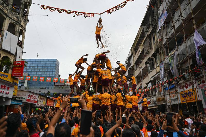 A young Hindu devotee hangs on to a rope after breaking a dahi-handi (curd-pot) suspended in the air as a human pyramid collapses beneath him during celebrations for the 'Janmashtami' festival, which marks the birth of Hindu deity Krishna, in Mumbai. AFP
