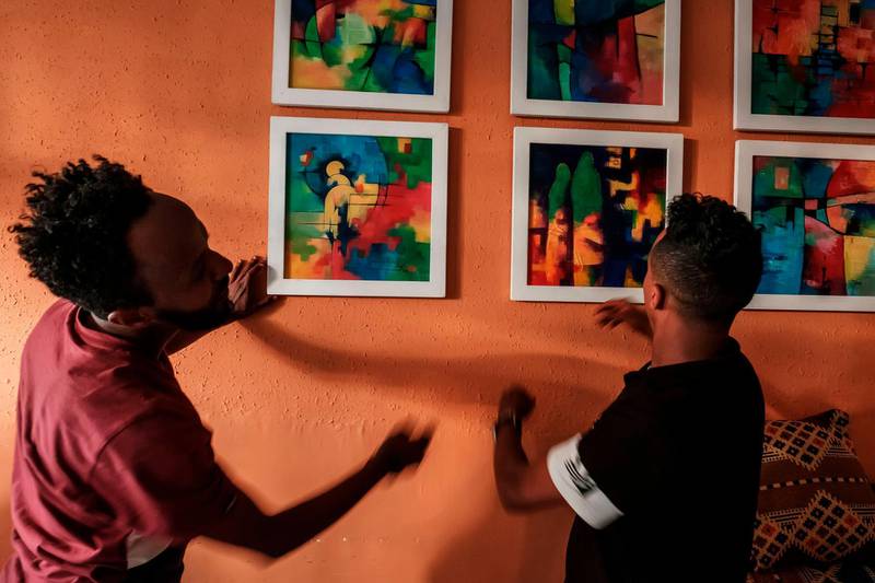 Eritrean painter Noah Mulubrhan arranges framed paintings with staff at a coffee shop as he prepares an exhibition of his paintings in that shop in Addis Ababa. AFP