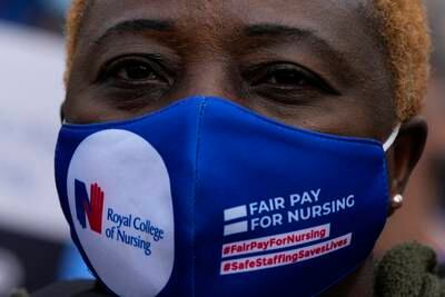 A health worker wears a mask which bears a slogan asking for fair pay for nurses during a demonstration about pay in the UK's National Health Service, in London.