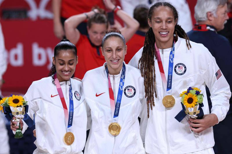 Brittney Griner with teammates Diana Taurasi and Skylar Diggins posing for pictures with their gold medals on the podium during the medal ceremony for the women's basketball competition of the Tokyo 2020 Olympic Games. AFP