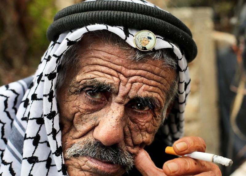 A Palestinian in Ramallah wearing a keffiyeh, similar to the one worn by Yasser Arafat, has a pin with the portrait of late Palestinian leader. Abbas Momani/AFP Photo