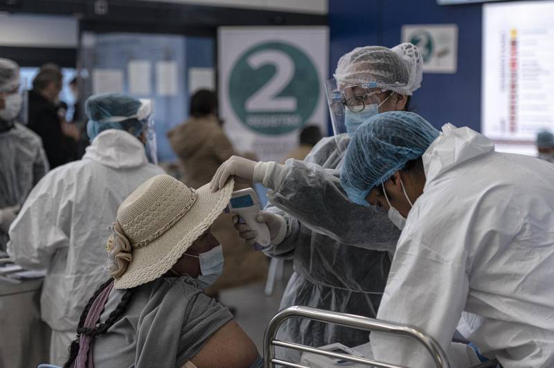 Healthcare workers take a resident's temperature before administering a dose of the Sputnik V Covid-19 vaccine at South Hospital in El Alto, Bolivia. Bloomberg