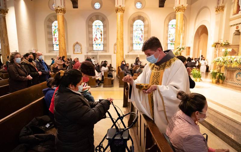 Rev. Russels Governale serves communion during a Spanish-language Easter service at St. Bartholomew Roman Catholic Church, Sunday, April 4, 2021, in New York. The parish has lost 80 members to COVID-19. (AP Photo/Mark Lennihan)