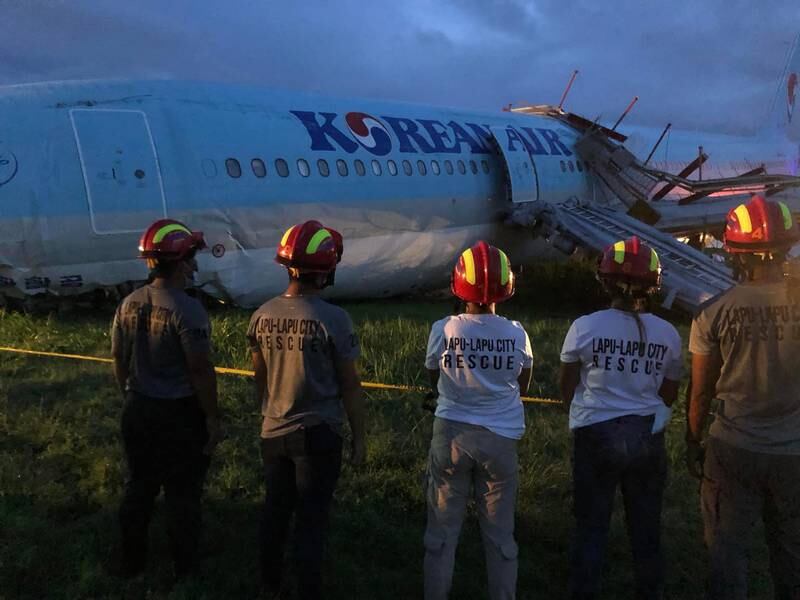 Rescue personnel stand next to the damaged aircraft. EPA