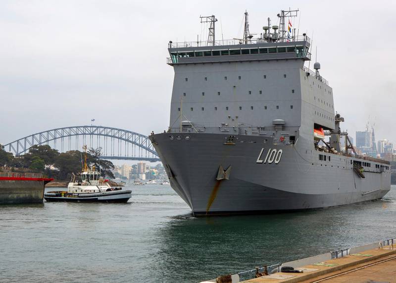 In this photo provided by the Australian Department of Defense, HMAS Choules departs from a fleet base in Sydney. Australia is deploying military ships to help communities ravaged by wildfires that destroyed homes and sent thousands of residents and holidaymakers fleeing to the shoreline. AP