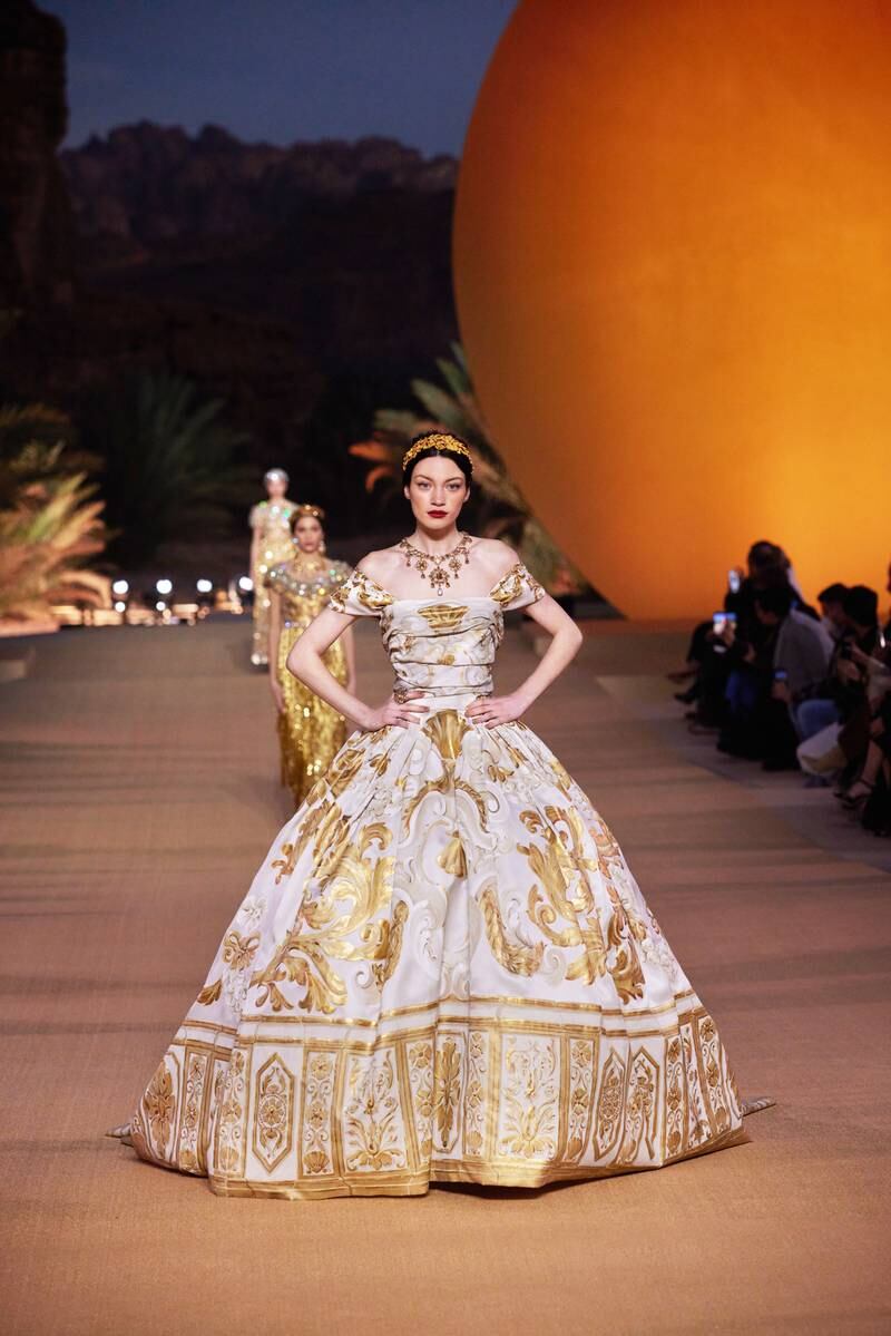 The show opened with a white gown of diaphanous silk, hand-painted with golden rococo swirls.