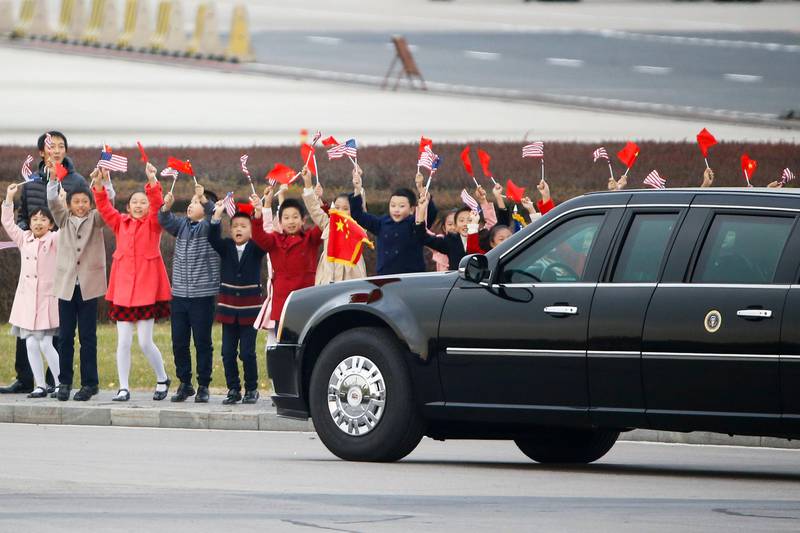 Children wave to the car carrying US President Donald Trump and first lady Melania after their arrival at the Beijing Capital International Airport in China. Thomas Peter / EPA