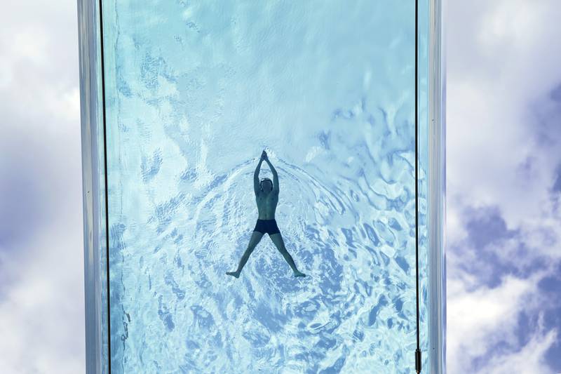 A man swims in the Sky Pool, a transparent swimming pool suspended 35 metres above ground between two apartment buildings, during hot weather in Nine Elms, central London. PA