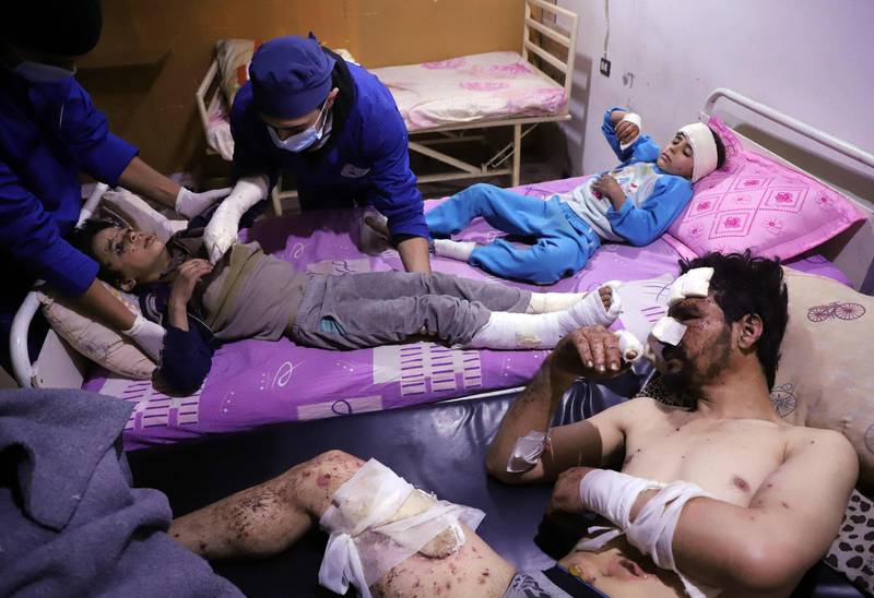 Doctors tend to ten-year-old Omar who was injured in an air strike that killed several members of his family on their home in Otaybah, in Syria's rebel-held enclave of Eastern Ghouta, as his father and seven-year-old sister, Manar, watch on at a make-shift hospital on February 25, 2018.  Amer Almohibany / AFP