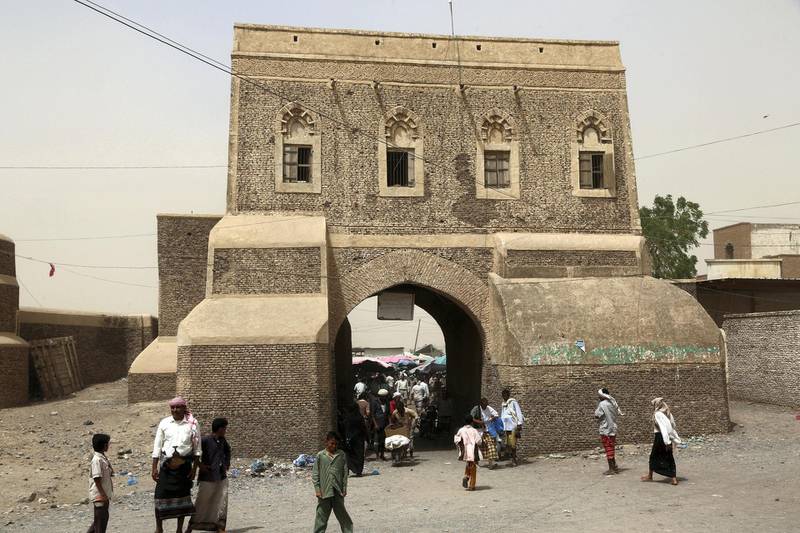 A picture taken on February 24, 2018 shows Yemenis walking through a gateway into a market in the ancient city of Zabid, a UNESCO World Heritage Site currently on the list of World Heritage in danger, in the western Hodeidah province. (Photo by ABDO HYDER / AFP)