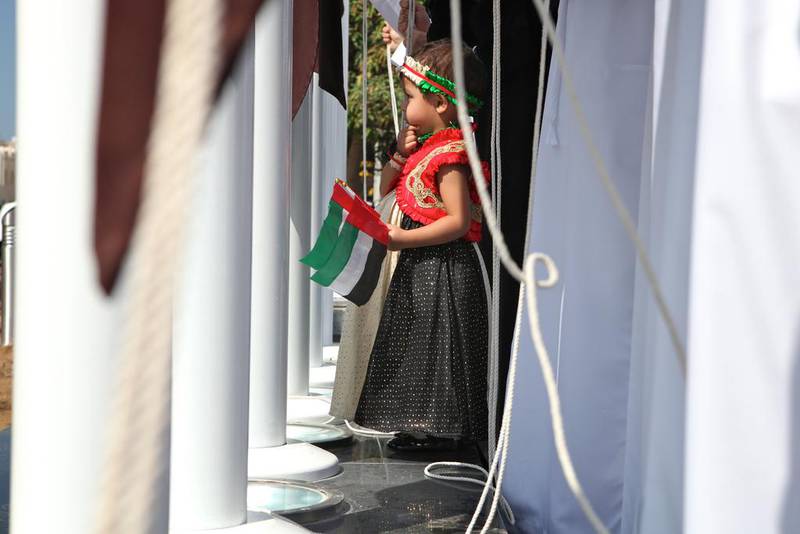 A child holds two UAE flags outside Abu Dhabi Media's head office in the capital. Brian Kerrigan / The National.