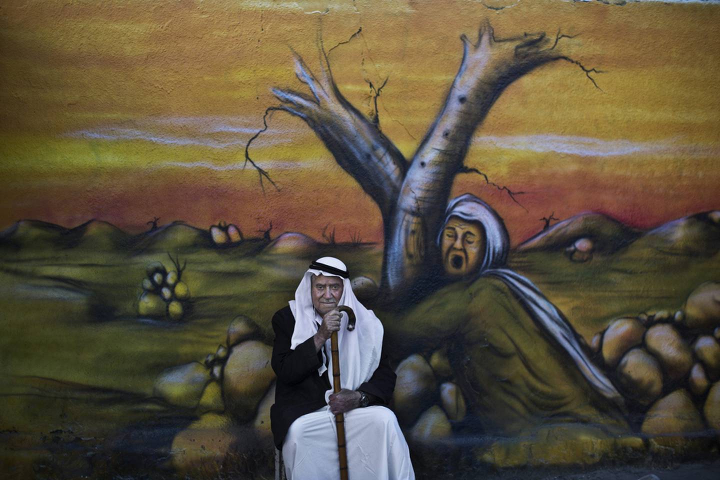 Palestinian refugee Mohammed Emtair, 85, in front of a mural depicting the Israeli-Palestinian conflict, in Kalandia refugee camp, between Jerusalem and the West Bank city of Ramallah. 