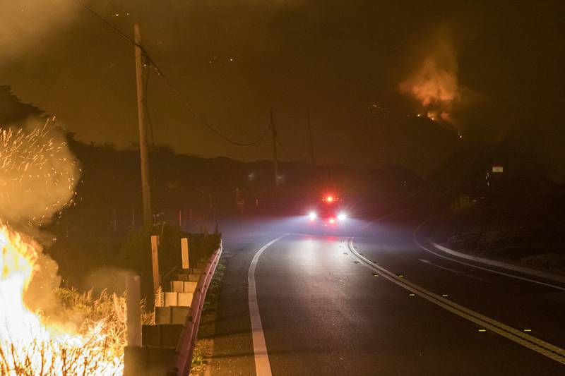 An emergency vehicle passes along Highway 1 near Big Sur, as wildfires burn.
