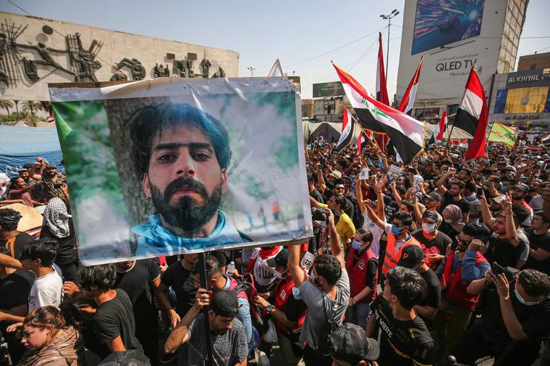 People hold up a picture of a slain protester as they gather with national flags for a demonstration in Tahrir Square in the centre of Iraq's capital Baghdad. AFP