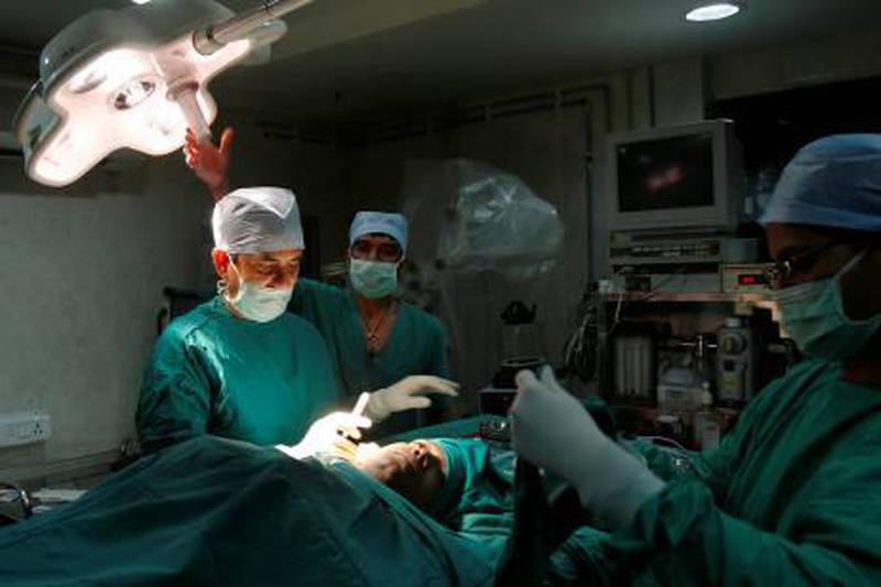 Dr Manoj Kumar J Manwani (L), senior consultant in cosmetic and plastic surgery, and his team perform cosmetic surgery inside a hospital operation theatre in Mumbai May 9, 2008. For years, Indian women have been relying on the surgeon's knife for that perfect body, that flawless face, and now, the men are muscling in. Body enhancing procedures are no longer only for the female, the self-conscious or the wealthy, with India's economic boom spawning a new breed of male, middle-class professionals with the desire to look good and the money to make it happen. Picture taken May 9, 2008.     To match INDIA-MEN/SURGERY     REUTERS/Punit Paranjpe (INDIA)