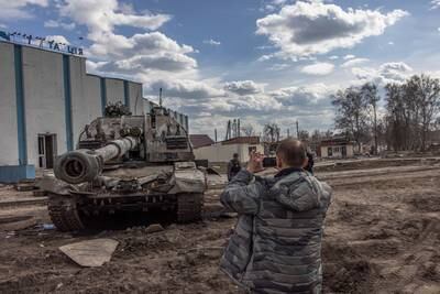 A resident takes photos of a destroyed Russian tank next to the railway station where the Russian forces were stationed, in Trostyanets, a town recaptured by the Ukrainian army. EPA