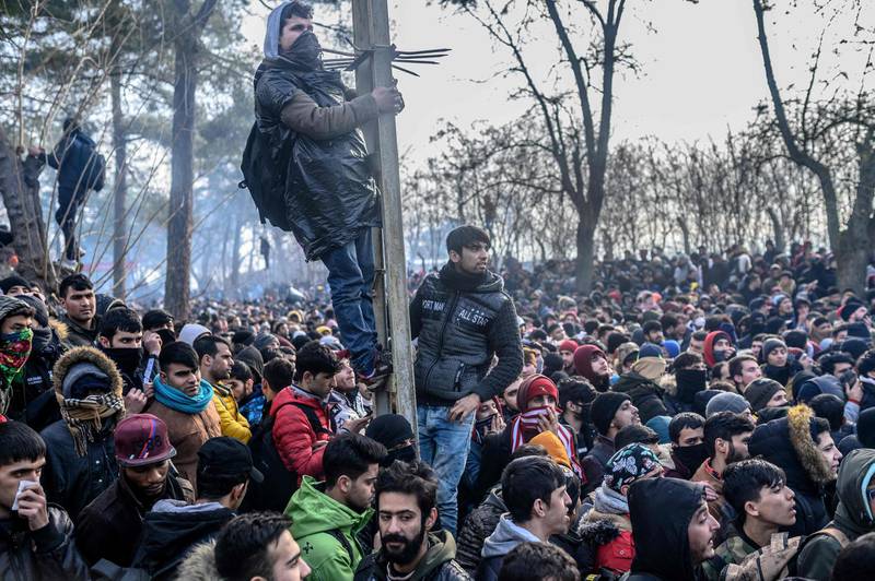 TOPSHOT - Migrants gather inside the buffer zone of the Turkey-Greece border, at Pazarkule, in Edirne district, on February 29, 2020. Thousands of migrants stuck on the Turkey-Greece border clashed with Greek police on February 29, 2020, according to an AFP photographer at the scene. Greek police fired tear gas at migrants who have amassed at a border crossing in the western Turkish province of Edirne, some of whom responded by hurling stones at the officers. The clashes come as Greece bolsters its border after Ankara said it would no longer prevent refugees from crossing into Europe following the death of 33 Turkish troops in northern Syria. / AFP / BULENT KILIC
