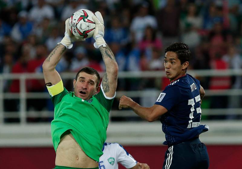 Uzbekistan's goalkeeper Ignatiy Nesterov, left, saves the ball against Muto. AP Photo