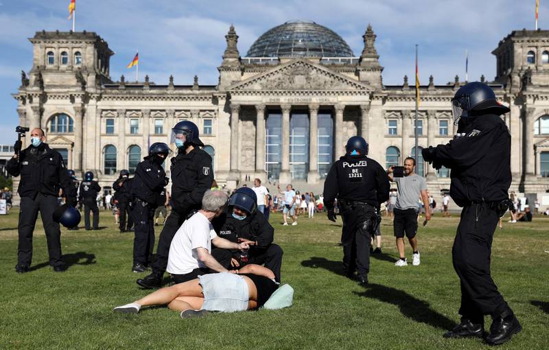 A police officer talks to demonstrators on the ground next to the Reichstag during a protest against the government's restrictions amid the coronavirus disease (COVID-19) outbreak, in Berlin, Germany. REUTERS