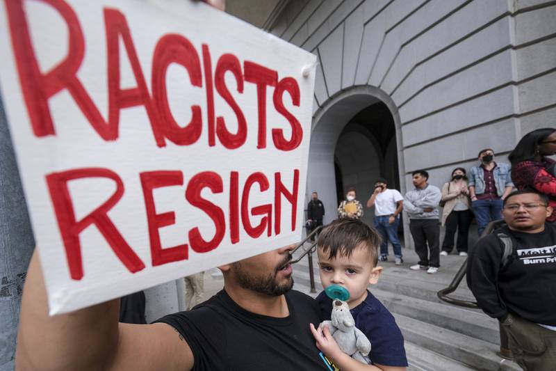 Shervin Aazami, holding his son Barrett and a sign, protests outside City Hall during the Los Angeles Council meeting. AP